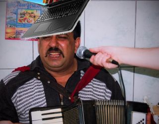 Ne modernizăm vizibil! Un politician a izbit un lăutar cu laptopul în frunte, ca să plătească în bitcoin